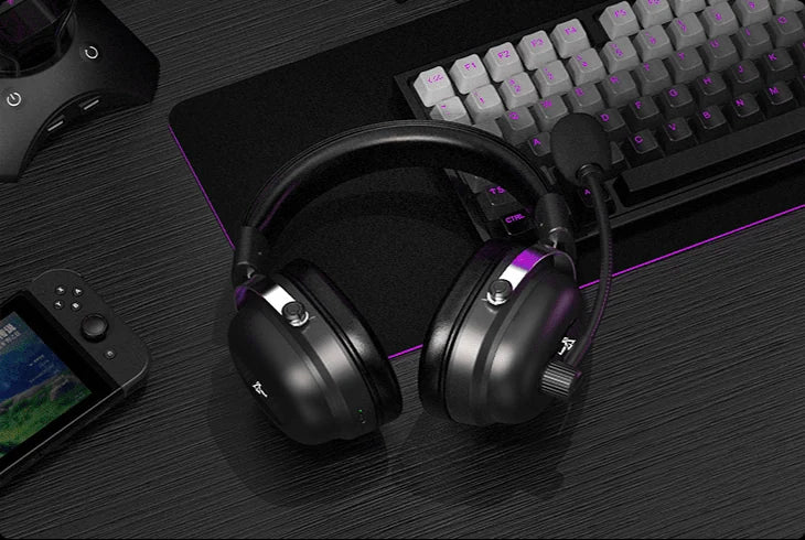 Commander headset resting on a desk between a keyboard and handheld console